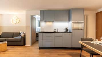 Una cucina moderna con mobili grigi, forno integrato e zona pranzo con tavolo e sedie.