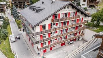 Un hotel a più piani con balconi e una località sciistica sullo sfondo.