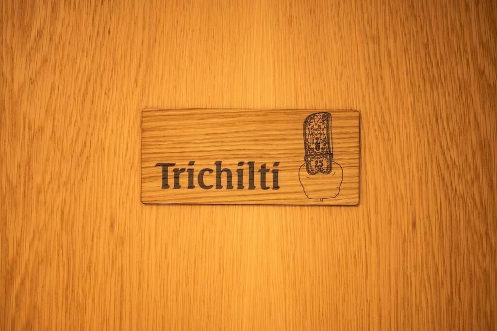 A wooden plaque with the word 'Trichili' and a drawing of a hand.