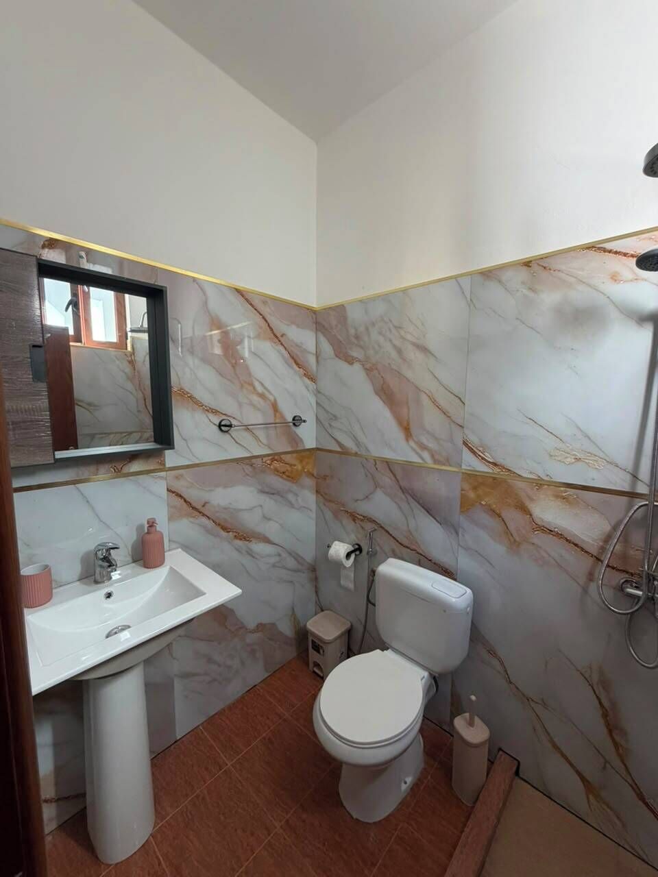 A bathroom with a white sink, toilet, and shower.