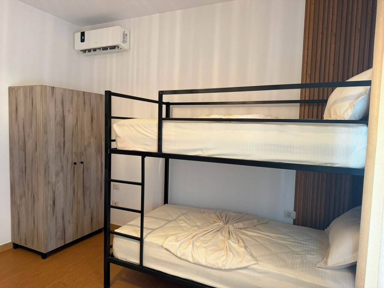 A bunk bed with a wardrobe and an air conditioning unit.