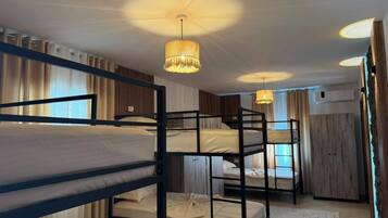 Een kamer met stapelbedden, een plafondventilator en een hanglamp.