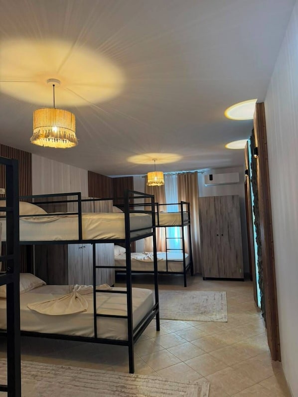 A room with bunk beds, a chandelier, and a window with curtains.