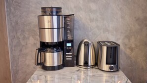 Une cuisine équipée d’une machine à café, d’une bouilloire, d’un grille-pain et de trois bougies allumées posées sur le comptoir.