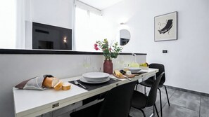 A modern dining area with a white table, black chairs, and a vase of flowers.