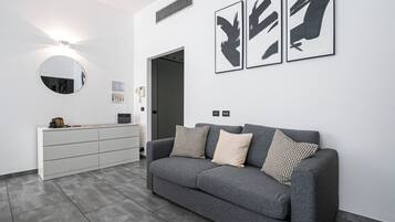A modern reception area with a grey sofa, a white console, and black abstract wall art.