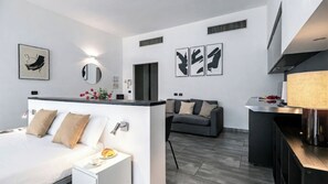 Ein modernes Hotelzimmer mit einem Bett, einem Nachttisch und einem grauen Sofa.