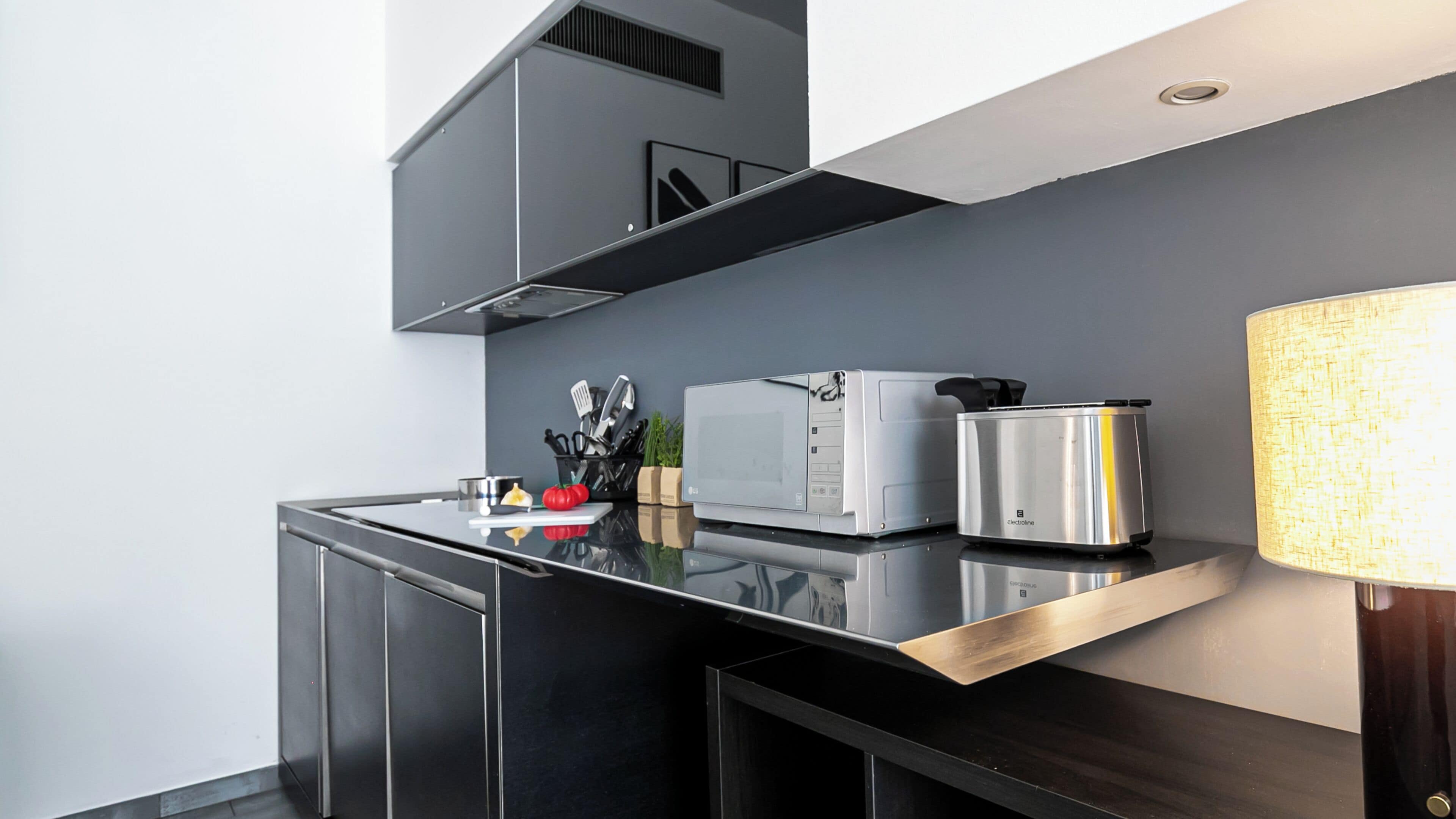 A modern kitchen with a microwave, toaster, and kettle on a black countertop.