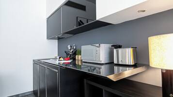 A modern kitchen with a microwave, toaster, and kettle on a black countertop.