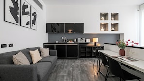 A modern kitchen with a central island, a dining area with a table and chairs, and a living area with a sofa.