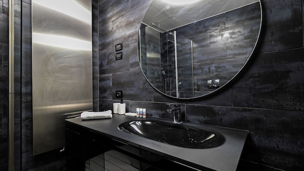 Une salle de bain moderne avec un lavabo noir, un grand miroir et un porte-serviettes.