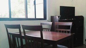 Une pièce comprenant une table et des chaises, un téléviseur et une fenêtre donnant sur un paysage verdoyant.