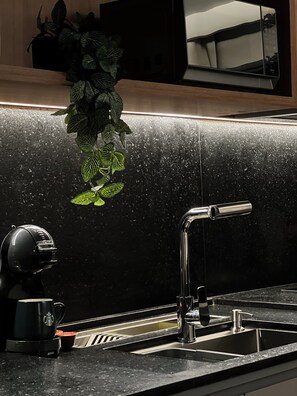 A kitchen counter with a coffee maker, a sink, and a plant. - Fully equipped apartment •  Excellent location with garage. (Goiânia)
