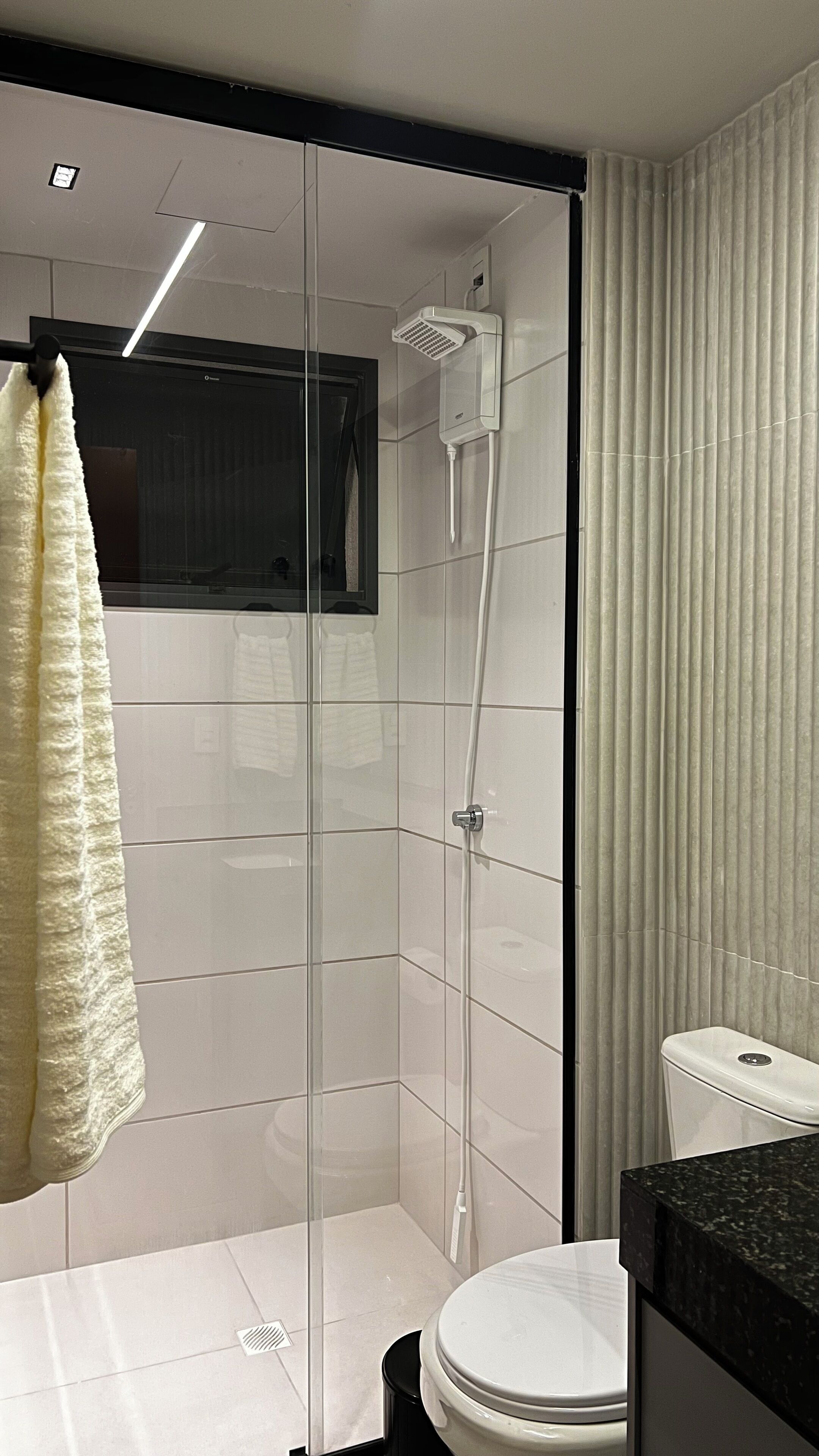 Un bagno moderno con doccia vetro, un water e un lavabo con piano nero.