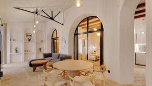 A spacious living area with a round wooden table and chairs, a grey sofa, and a bookshelf with books and plants. - A Authentic 3-BR/2Ba in Opera - Grands Boulevards (Paris)