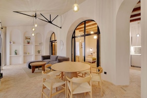 A spacious living area with a round wooden table and chairs, a grey sofa, and a bookshelf with books and plants. - A Authentic 3-BR/2Ba in Opera - Grands Boulevards (Paris)