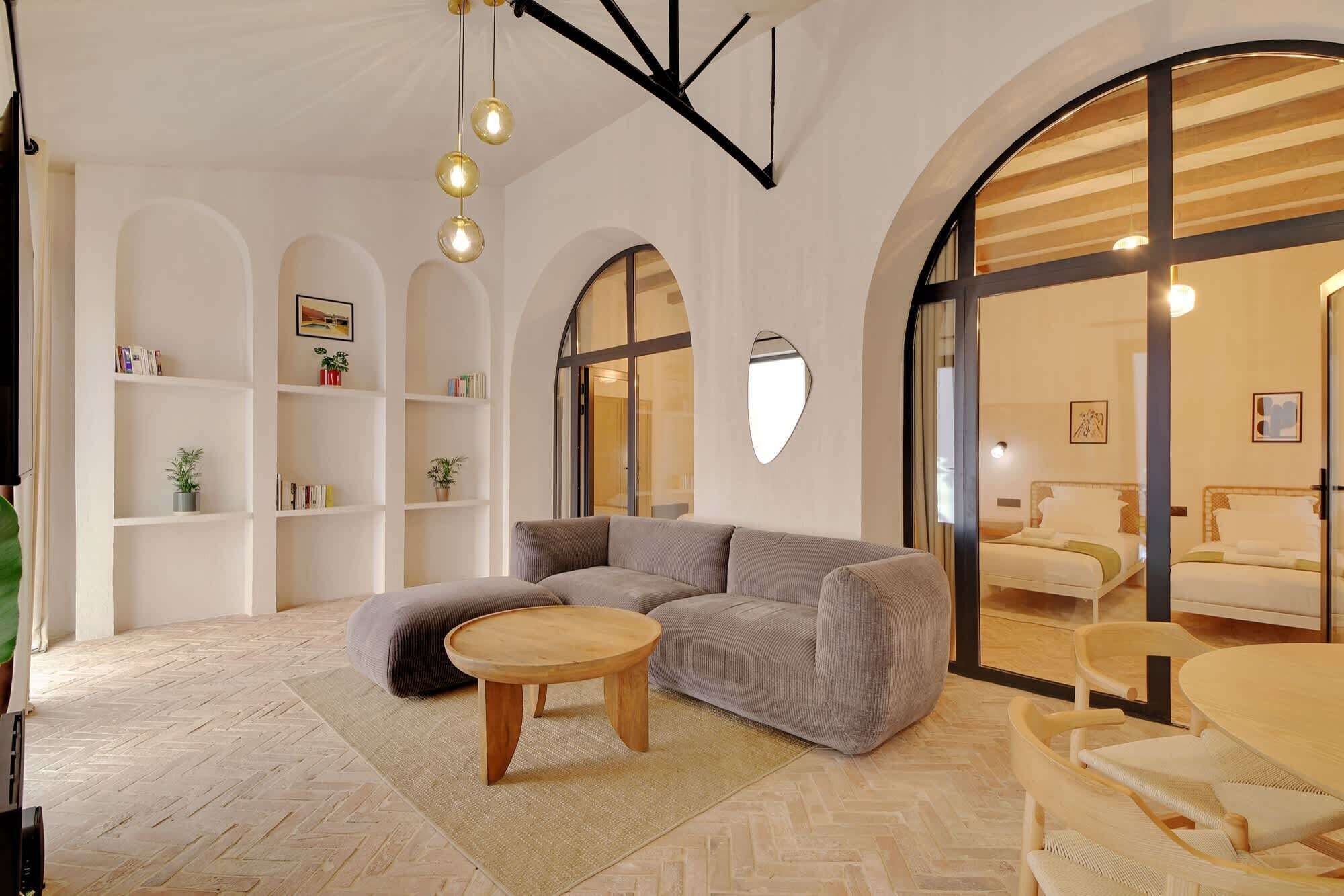 A modern living room with a sectional sofa, a round wooden coffee table, and a herringbone floor pattern.