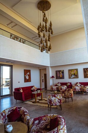 Ein geräumiger Innenraum mit hoher Decke, einer Chandelier, mehreren Sitzbereichen und Kunstwerken an den Wänden.
