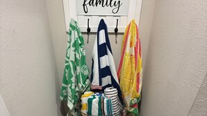 Un rincón con una pared blanca, un letrero que dice 'familia' y un banco con una cesta de toallas dobladas.
