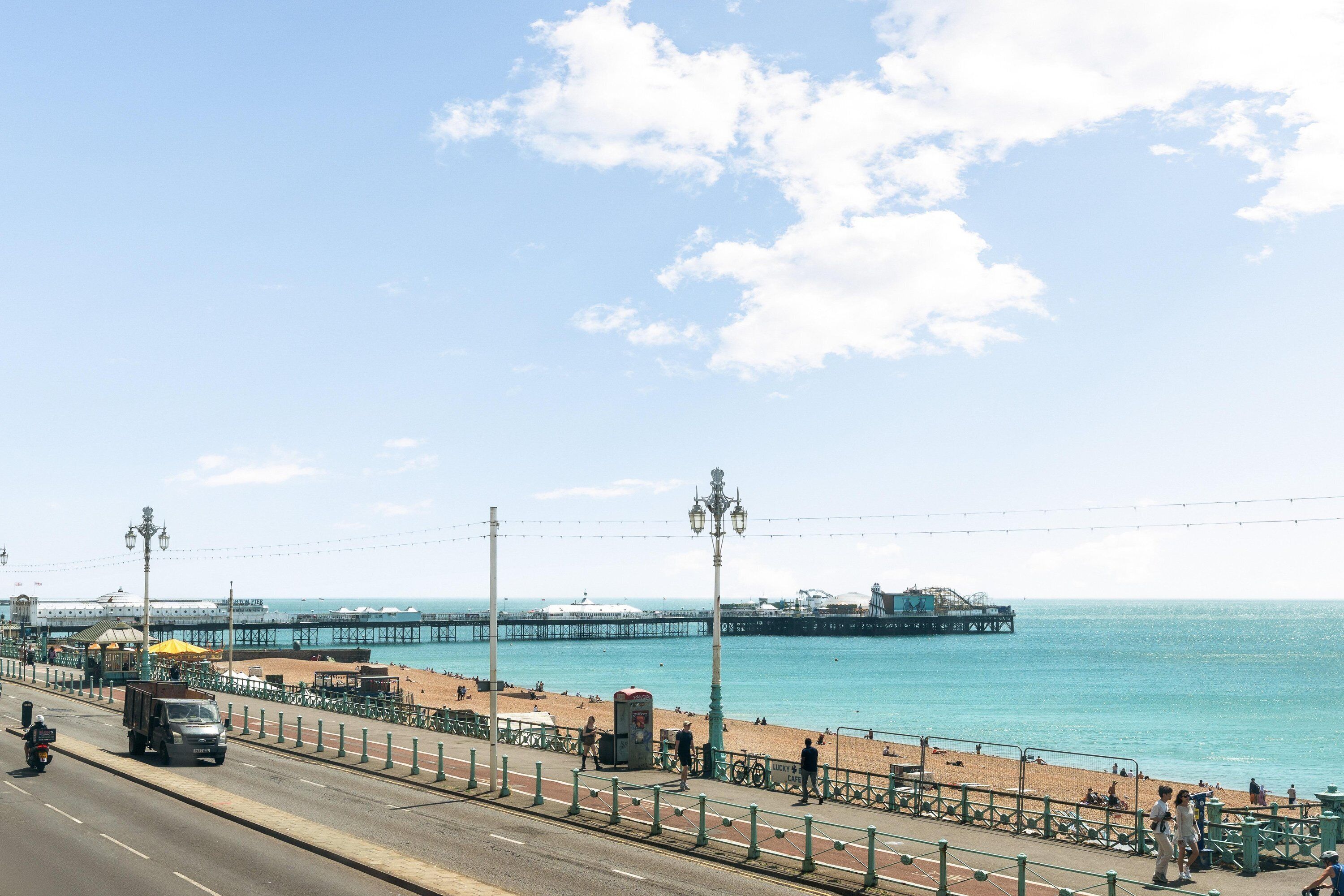 A coastal road with a beach and pier in the background.