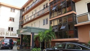 Un hotel de diverses plantes amb balcons, entrada coberta i plantes en testos.