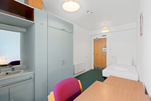 A hotel room with a bed, a desk, a chair, a bathroom, and a view of the hallway. - Kings Residence 4 | By My Getaways (Brighton)