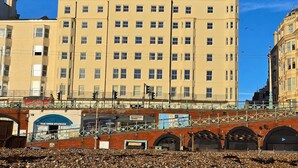 A multi-story building with a flat facade, numerous windows, and a pedestrian bridge with a metal railing. - Kings Residence 5 | By My Getaways (Brighton)