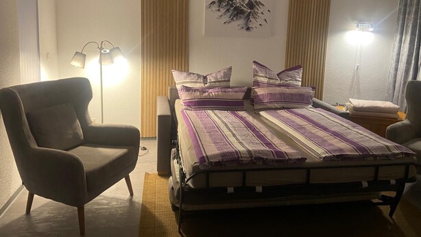 Ein Hotelzimmer mit einem Bett, zwei Stühlen, einer Lampe und einem Wandbild.