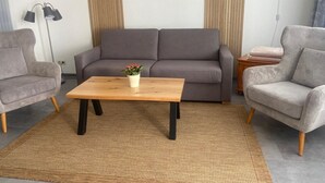 Ein Wohnzimmer mit grauem Sofa, einem Holztisch, einem grauen Sessel und einer Stehlampe.