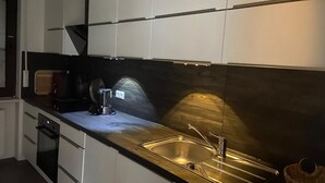 Eine moderne Küche mit Spüle aus Edelstahl, einer Kaffeemaschine und einem Toaster.