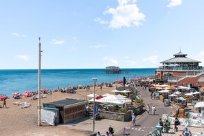 A beachside promenade with beach umbrellas, a pier, and a building with a dome roof. - Kings Residence 8 | By My Getaways (Brighton)