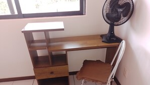 A room with a wooden desk, a chair, a standing fan, and a window. - Charming 2-bedroom house with AC in vibrant Salvador (Salvador)