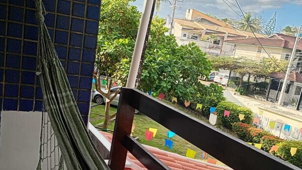A hammock on a balcony with a view of a residential area and a tiled floor. - Charming 2-bedroom house with AC in vibrant Salvador (Salvador)