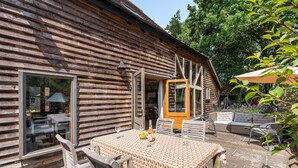 Eine Holzhütte mit Essbereich, inklusive Tisch und Stühlen, einer überdachten Terrasse und Blick auf den umliegenden Wald.