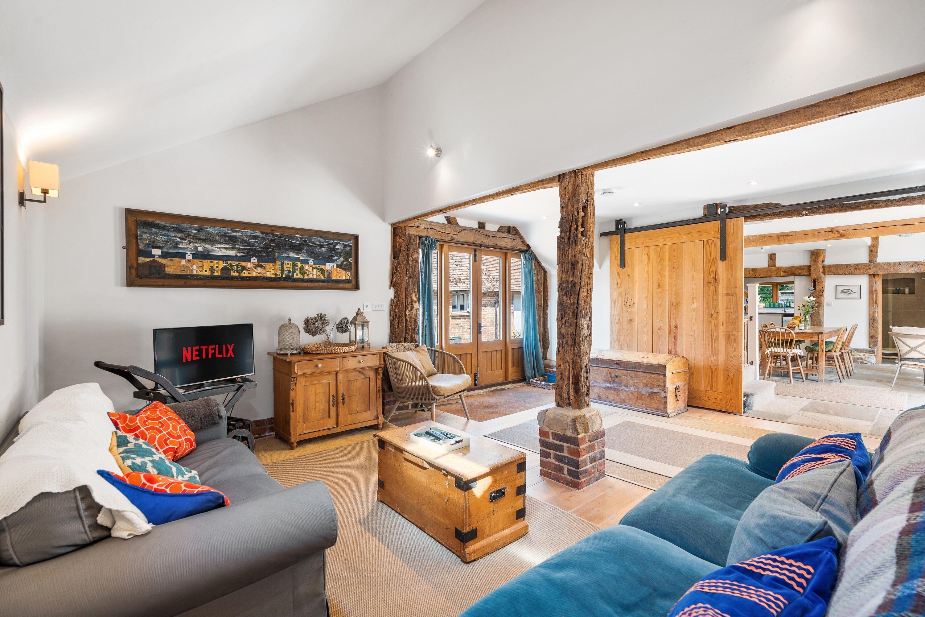 A living room with a sofa, a television, a wooden cabinet, and a large window.