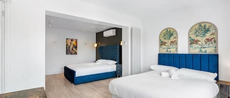 A modern bedroom with two beds, a wooden floor, and a large window with artwork.