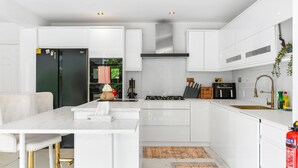 A modern kitchen with white cabinetry, a central island, and a built-in stove.
