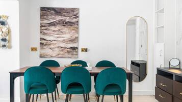 A dining area with a marble floor, a large abstract painting, and teal chairs.