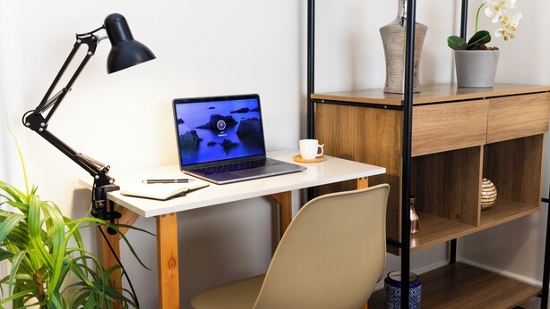 A workspace with a laptop, desk lamp, notebook, pen, and a potted plant. - 3 Quartos a 100m da Praia com AC  (Rio de Janeiro)