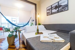 Ein Hotelzimmer mit Bett, einer Hängematte, einem Balkon und Blick auf die Stadt.
