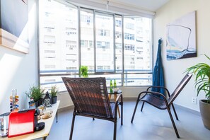 Ein Balkon mit Korbstühlen, einem kleinen Tisch mit Flaschen und einem roten Gerät.