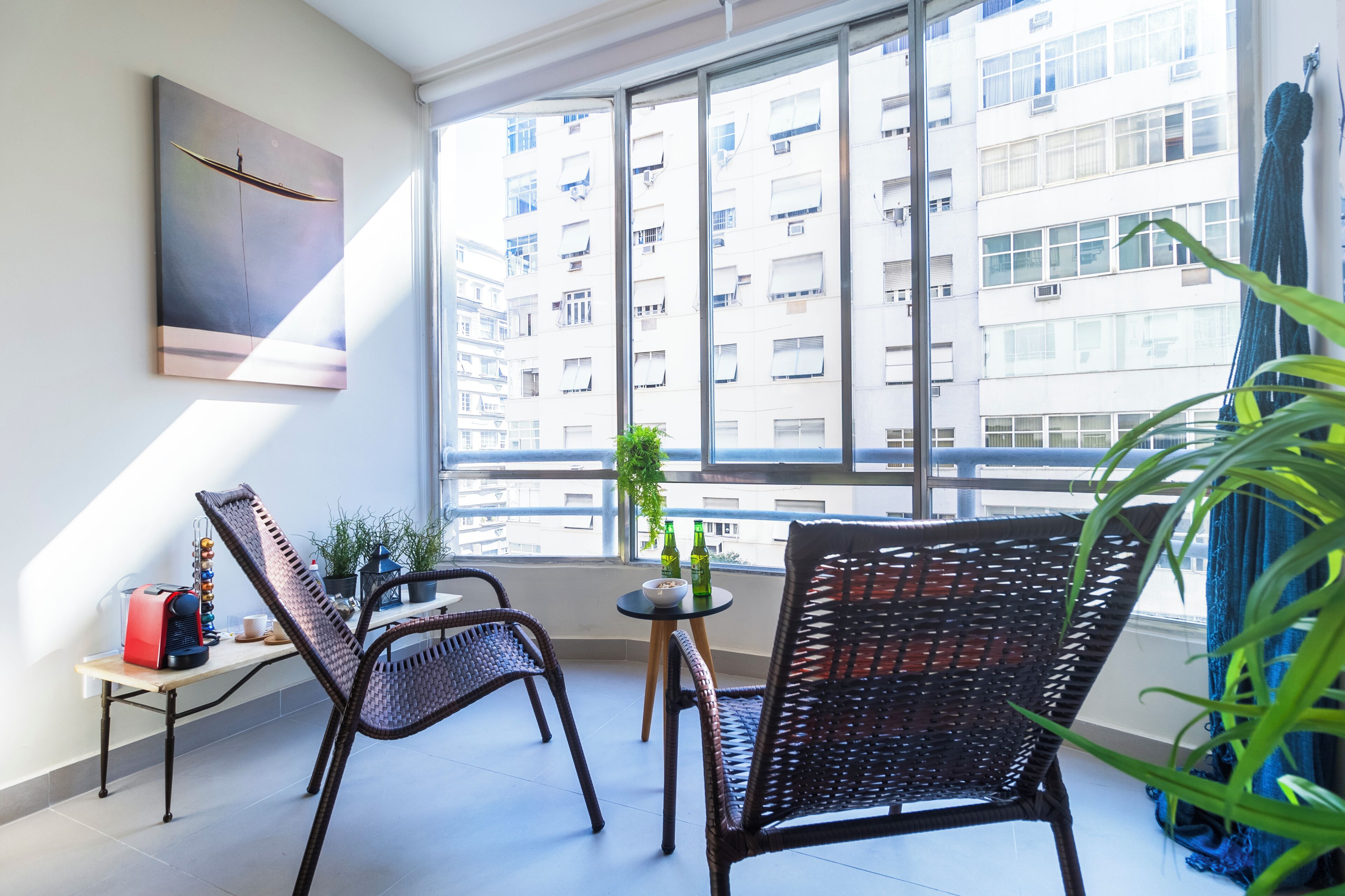 Een balkon met rieten stoelen, een tafeltje en een plant in pot.