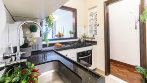 A modern kitchen with a stainless steel sink, a stove, and a window with a view of the outside. - 3 Quartos a 100m da Praia com AC  (Rio de Janeiro)