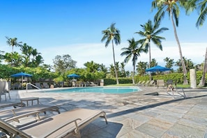 A pool area with lounge chairs, umbrellas, and palm trees. - New Listing, Kanaloa, Golf Course Views, AC (Kailua-Kona)