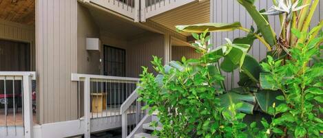A multi-story building with balconies, a staircase, and lush greenery.