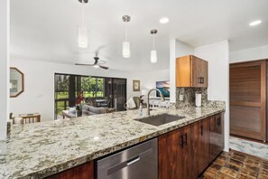 Eine moderne Küche mit einer Granit Arbeitsplatte, Edelstahlgeräten und Pendelleuchten.