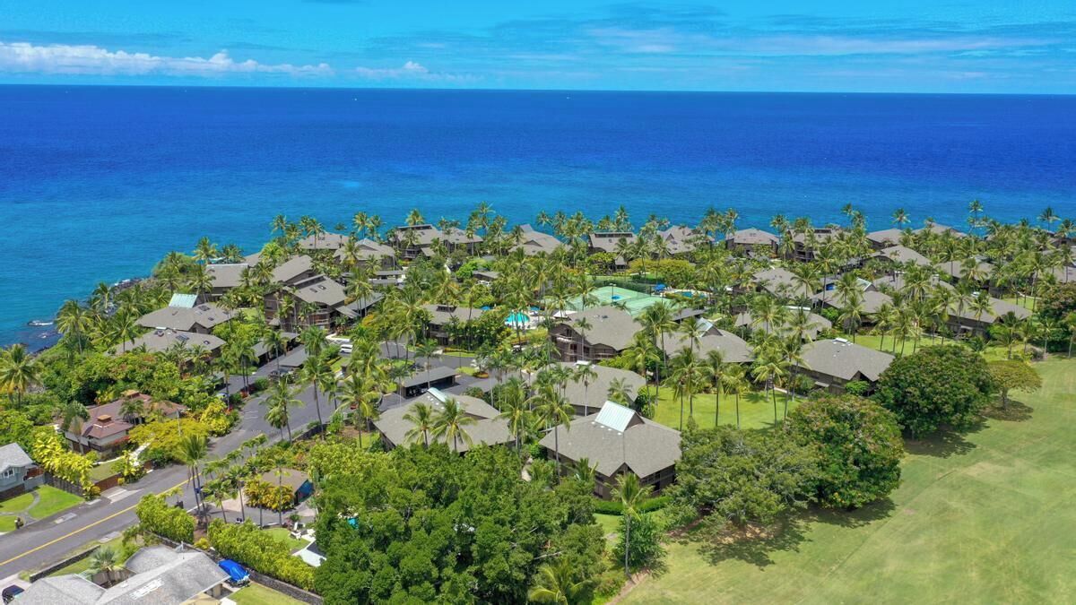 Una località balneare con diversi edifici in stile bungalow, una piscina centrale e vista sull'oceano.