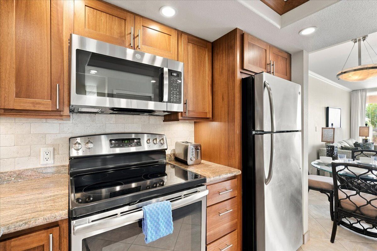 Una cocina con gabinetes de madera, electrodomésticos de acero inoxidable y una mesa de comedor de vidrio.