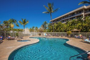 A swimming pool with multiple lanes, surrounded by palm trees and lounge chairs. - Maui Banyan H502 Renovated Partial Ocean View Condo Near Kamaole Beach II (Kihei)
