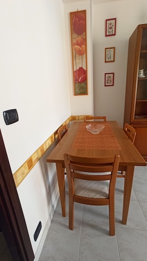 A dining area with a wooden table, chairs, a glass bowl, and a decorative wall piece. - Casa Stella Terminal (Perosa Argentina)